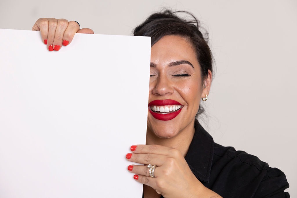 Kathy laughing while holding a white card in front of her face